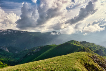 Fototapeta premium sun spots on meadow landscape with clouds. The formation and movement of clouds over the summer slopes of Adygea, Bolshoy Tkhach and the Caucasus Mountains 