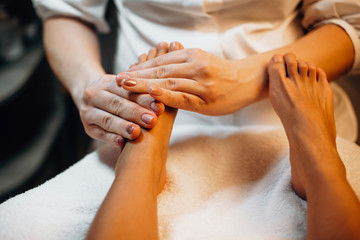 Careful spa worker is massaging client's feet before moving to the next spa procedure