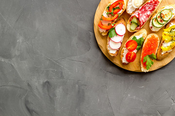 Set of bruschetta on cutting board on grey background top-down copy space