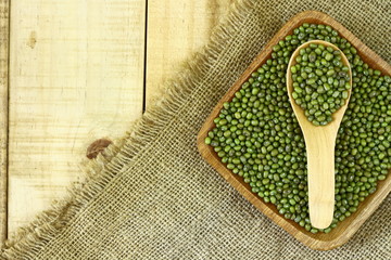 mung beans in wooden bowl and spoon on wooden table top. Copy space for text or editorial.