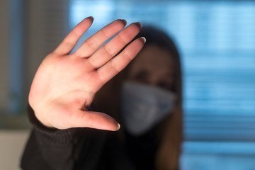 Prevent the spread of the Coronavirus Disease 2019 (COVID-19). Stop gesturing woman wearing a protective medical face mask. Selective focus