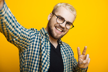 Close up portrait of a caucasian man with blonde hair and short beard looking through eyeglasses and making a selfie