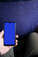 A man holds a modern smartphone in his hand when traveling on public transport