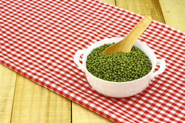 mung beans in ceramic bowl and wooden spoon with table cloth pattern scotch white red colour  