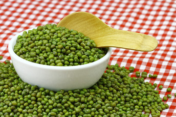 mung beans in ceramic bowl and wooden spoon with table cloth pattern scotch white red colour  