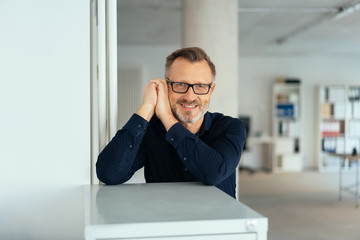 Relaxed friendly man leaning on an office cabinet