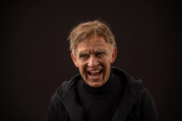 plastic makeup. makeup for cinema. old man on a black background. old man laughs