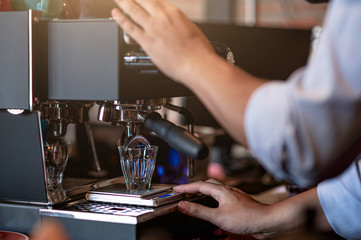 freshly brewed coffee is poured from the coffee machine into glass cups in the coffee shop