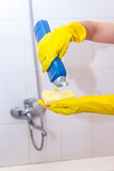 Woman in gloves putting cleaning chemistry to the sponge and want to clean up the bathroom
