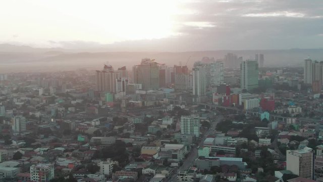 Aerial drone shot of the Cityscape of Quezon City, Manila, Philippines while sunrise