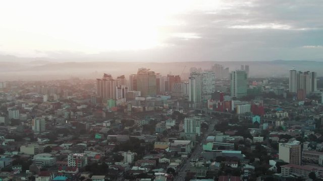 Aerial drone shot of the Cityscape of Quezon City, Manila, Philippines while sunrise
