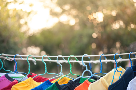 Line Of Multi Colored Shirts On Wooden Hangers