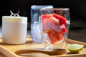Healthy fruits with portable blender on wooden tray getting ready for making a smoothie. Fresh strawberry and watermelon with ice; healthy and fresh concept.