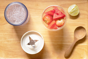 Healthy fruits with portable blender on wooden tray getting ready for making a smoothie. Fresh strawberry and watermelon with ice; healthy and fresh concept.