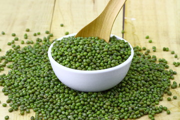 mung beans in ceramic bowl and spoon on wooden table top