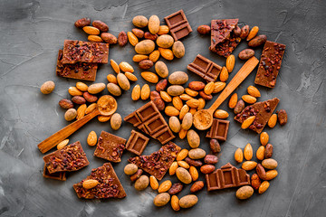Sweets background with chocolate pieces and nuts on grey stone table top-down