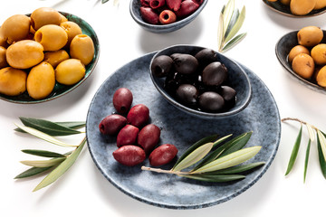 Olives, green, black and red, an assortment with leaves on a table