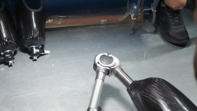 Production of a prosthetic leg. A man creates part of the leg. An engineer is testing the mechanical joint of a prosthetic leg. New sports body part