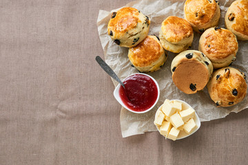 Scones with butter and jam on a brown background