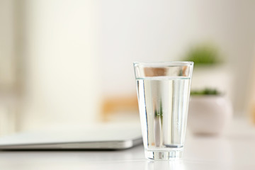 Glass of water with laptop on workplace in office