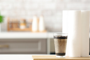 Glass of dirty water with filters on table in kitchen