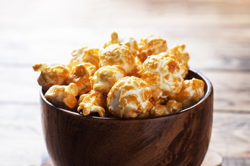 Popcorn in caramel glaze in wooden plates on a rustic table. Copy space.