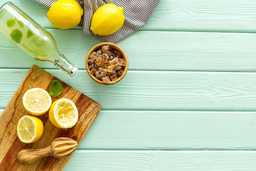 Make lemonade. Drink in bottle near utensil on green wooden background top-down copy space