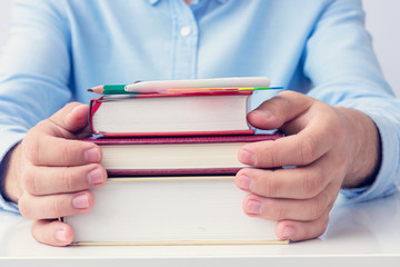 Concept of education. Student guy with stack of books, man's hands, cropped image, closeup