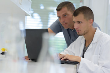 two men looking at laptop computer in a laboratory