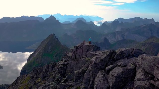 Aerial view of Man and woman at the top of the mountain. Beautiful view of the peaked tops of the Lofoten Islands. Norway 4k