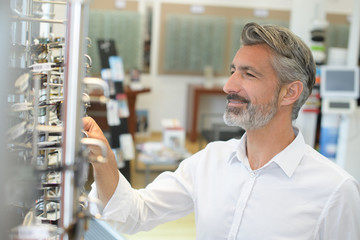 Obraz premium handsome senior man choosing sunglasses in store