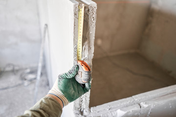 The construction worker measures with a tape measure Gypsum plate. Construction of internal walls...