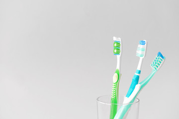 Tooth brushes in glass on light background