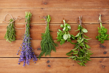 gardening, ethnoscience and organic concept - bunches of greens, spices or medicinal herbs on wooden background