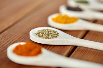 food, culinary and unhealthy eating concept - spoons with different spices on wooden table