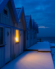 Illuminated window in a row of beach huts at night
