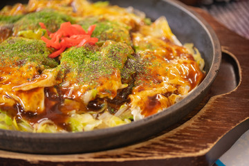 鉄板皿に乗ったソースのかかった広島風お好み焼き。