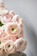 Spring background, flower Wallpaper. Persian buttercup. Bunch pale pink ranunculus flowers on light gray background. Vase on vintage wooden table. Wallpaper