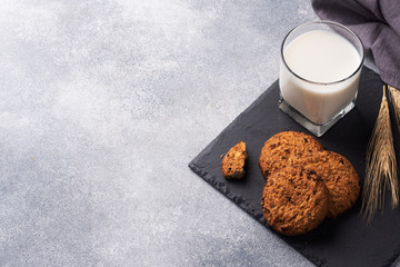Homemade cookies cereals oats and a glass of milk on the grey concrete table. Copy space.