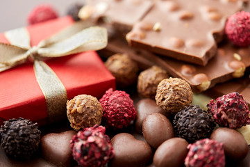 sweets concept - close up of handmade chocolate candies and red gift box