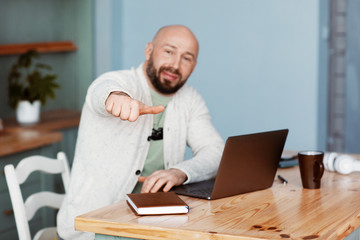 Portrait of a man working on a laptop and making an OK gesture to the side