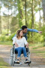 loving couple in wheelchair going for a walk outdoors