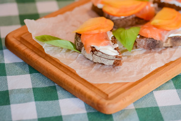 Slamon with mango and cheese sandwiches served on a cutting board over plaid background.