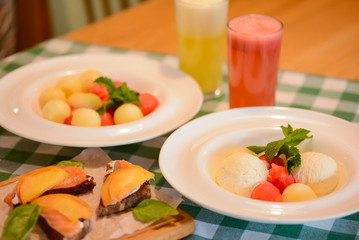 Sweet tasty salad with melon, peach fruit balls, brie, dorblu, mozarella cheese served in white square plate