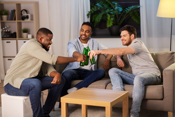 friendship, leisure and people concept - happy male friends drinking beer at home at night