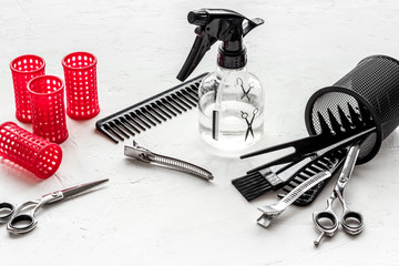 Hairdresser desk with combs, scicoors, spray and curlers on white background