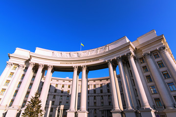 Fototapeta na wymiar Wide-angle landscape view of building with columns of Ministry of Foreign Affairs of Ukraine against blue sky. Ukrainian Trident is coat of arms, Flag of the Ukraine on the top of the building