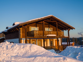 Fototapeta na wymiar Alpine-style hotel house in the Gornaya Salanga ski resort. The sun rises. Beautiful morning lighting