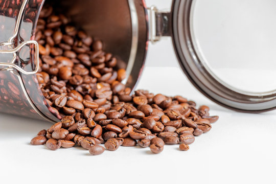 close up of grains of black coffee inside a coffee bottle isolated on white background with copy space.