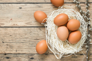 Easter decoration on wooden table with eggs in a nest, top view